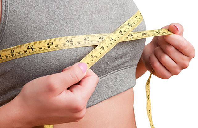 Sporty woman measuring up her chest, isolated in white